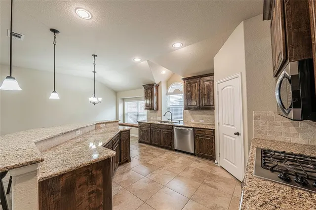 a large kitchen with granite countertop a stove oven and a sink
