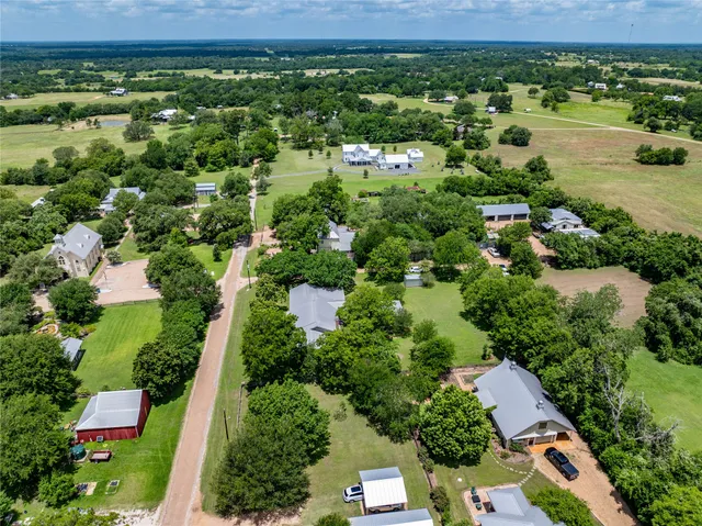 an aerial view of residential houses with outdoor space and trees