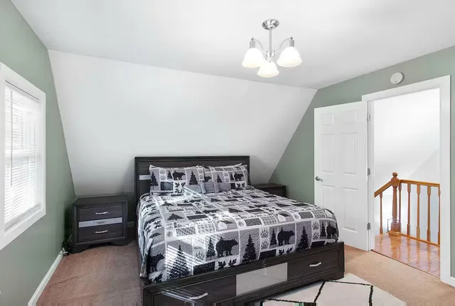 a bedroom with a bed next to a window and a chandelier