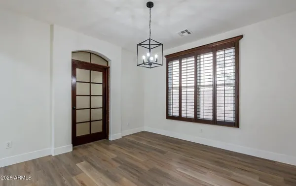 a view of a room with wooden floor chandelier and windows