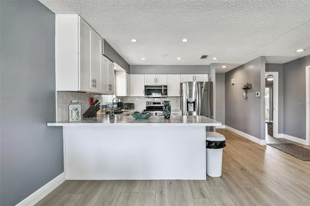 a view of kitchen with stainless steel appliances granite countertop a refrigerator a sink dishwasher and a stove with wooden floor