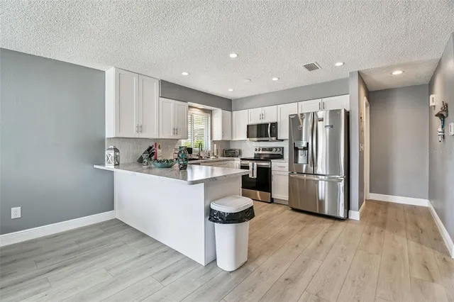 a kitchen with a refrigerator a white cabinets and wooden floor