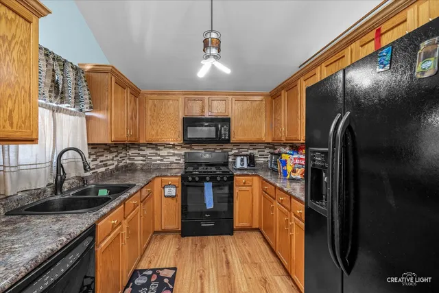 a kitchen with stainless steel appliances granite countertop a sink a stove top oven a refrigerator cabinets and a kitchen island