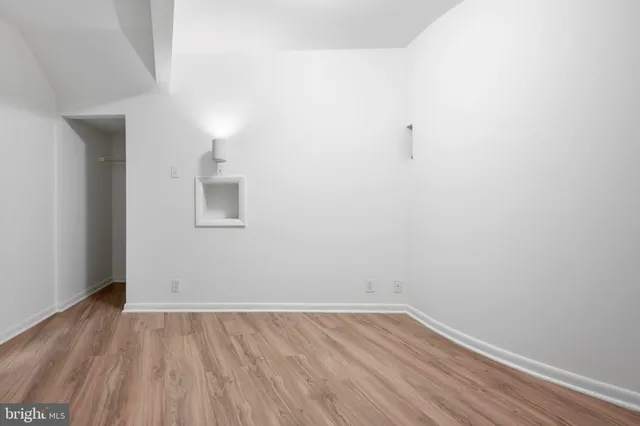 a view of an empty room with wooden floor and a bathroom