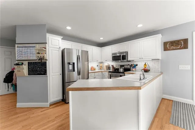 a kitchen with kitchen island granite countertop stainless steel appliances refrigerator cabinets dining table and chairs