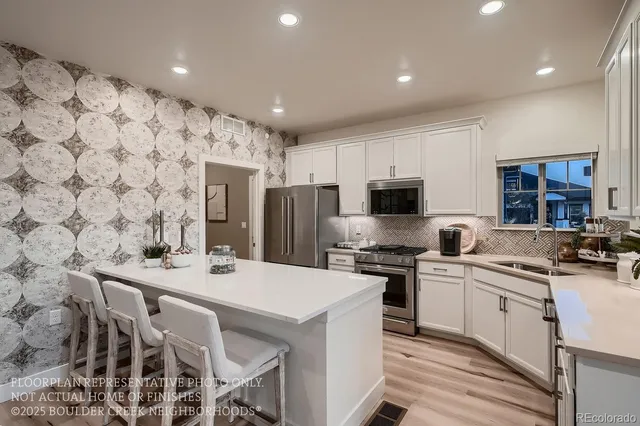 a kitchen with stainless steel appliances a stove a sink a microwave a refrigerator and cabinets