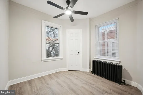 an empty room with wooden floor ceiling fan and windows