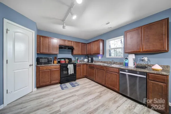 a kitchen with stainless steel appliances granite countertop a stove a sink dishwasher a dining table and chairs with wooden floor