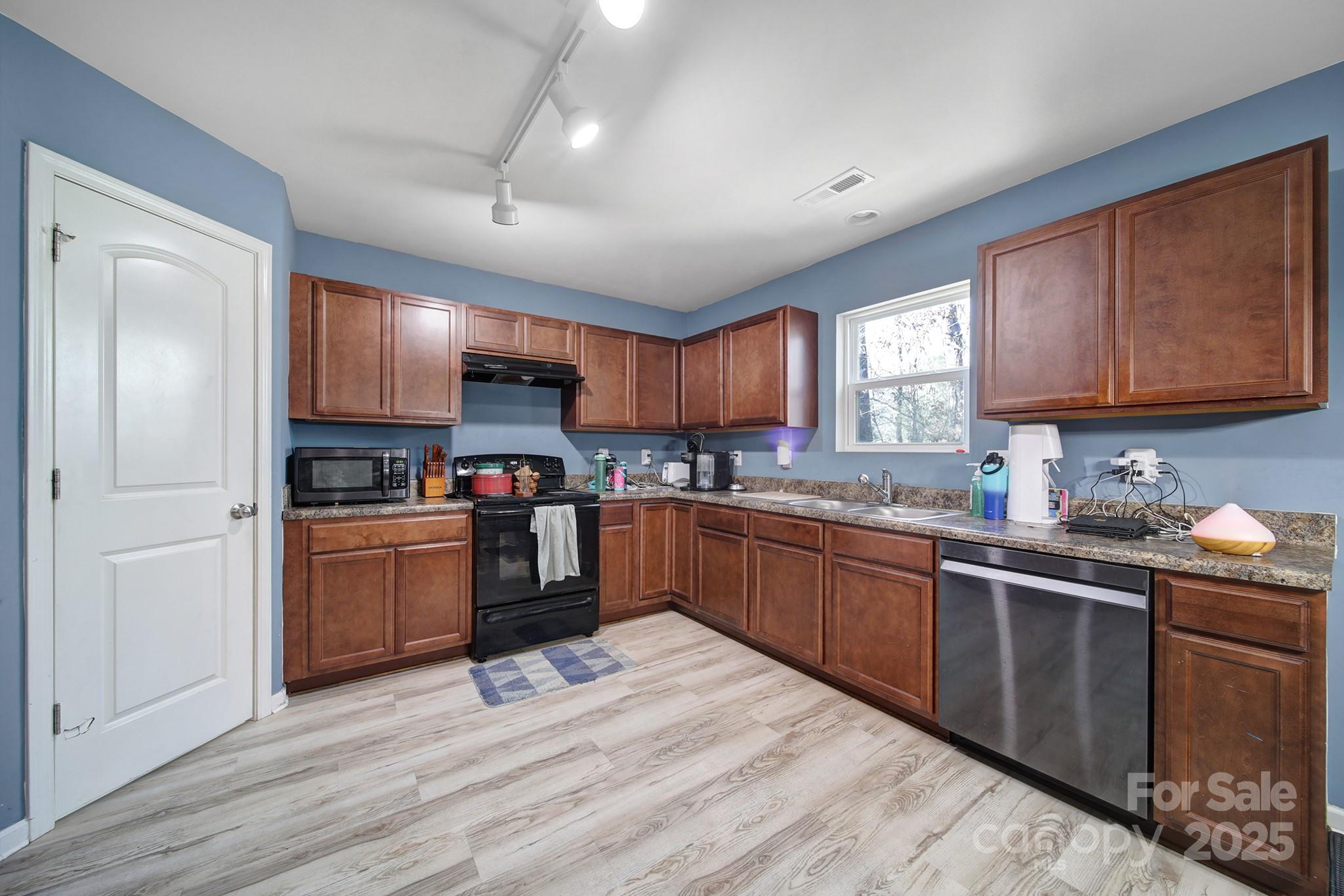 1708 Millwood Road Lancaster, SC 29720 - Photo 22 of 40 a kitchen with stainless steel appliances granite countertop wooden cabinets a refrigerator a sink a stove and a microwave