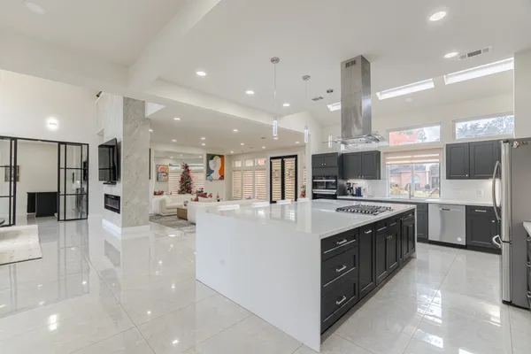 a large kitchen with stainless steel appliances a large counter top a stove and a refrigerator