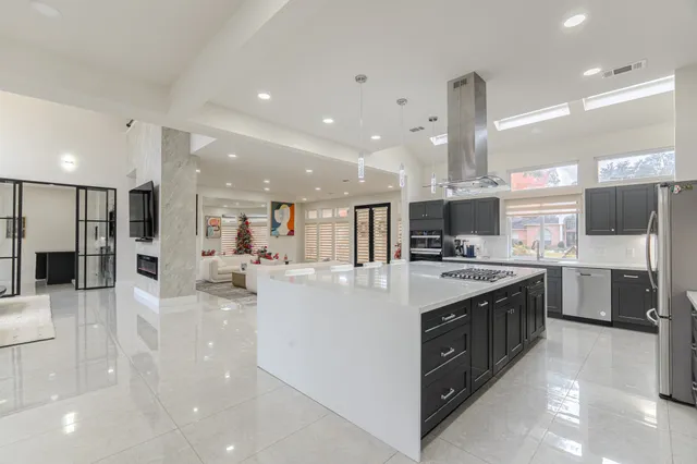 a large kitchen with stainless steel appliances a large counter top a stove and a refrigerator