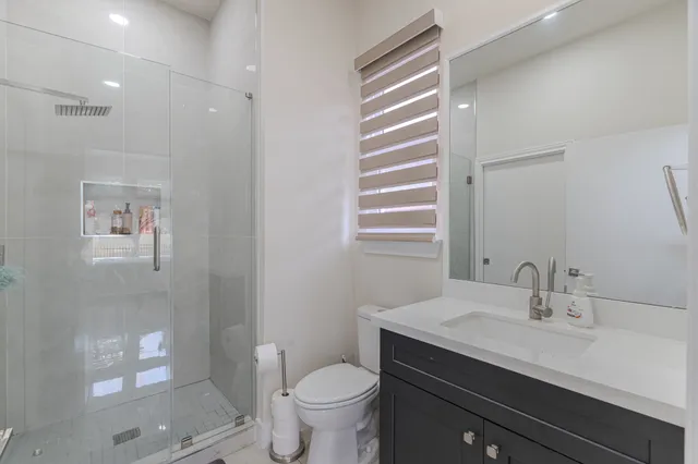 a bathroom with a sink a toilet a mirror and shower