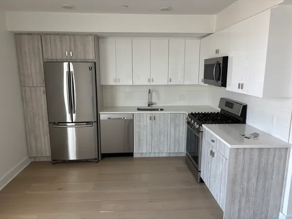 a kitchen with stainless steel appliances a refrigerator stove and white cabinets