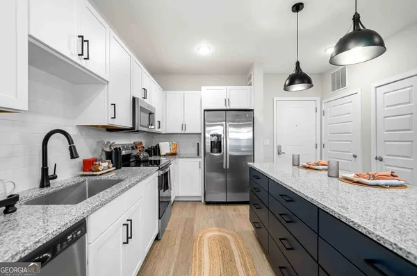 a kitchen with stainless steel appliances granite countertop a sink a stove and refrigerator