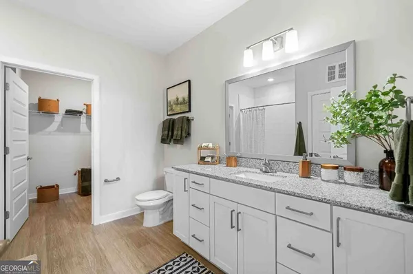 a spacious bathroom with a granite countertop sink a toilet a mirror and shower