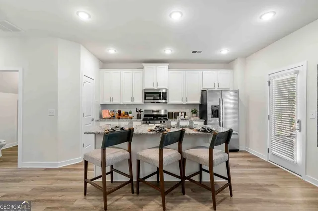 a kitchen with a dining table chairs refrigerator and cabinets