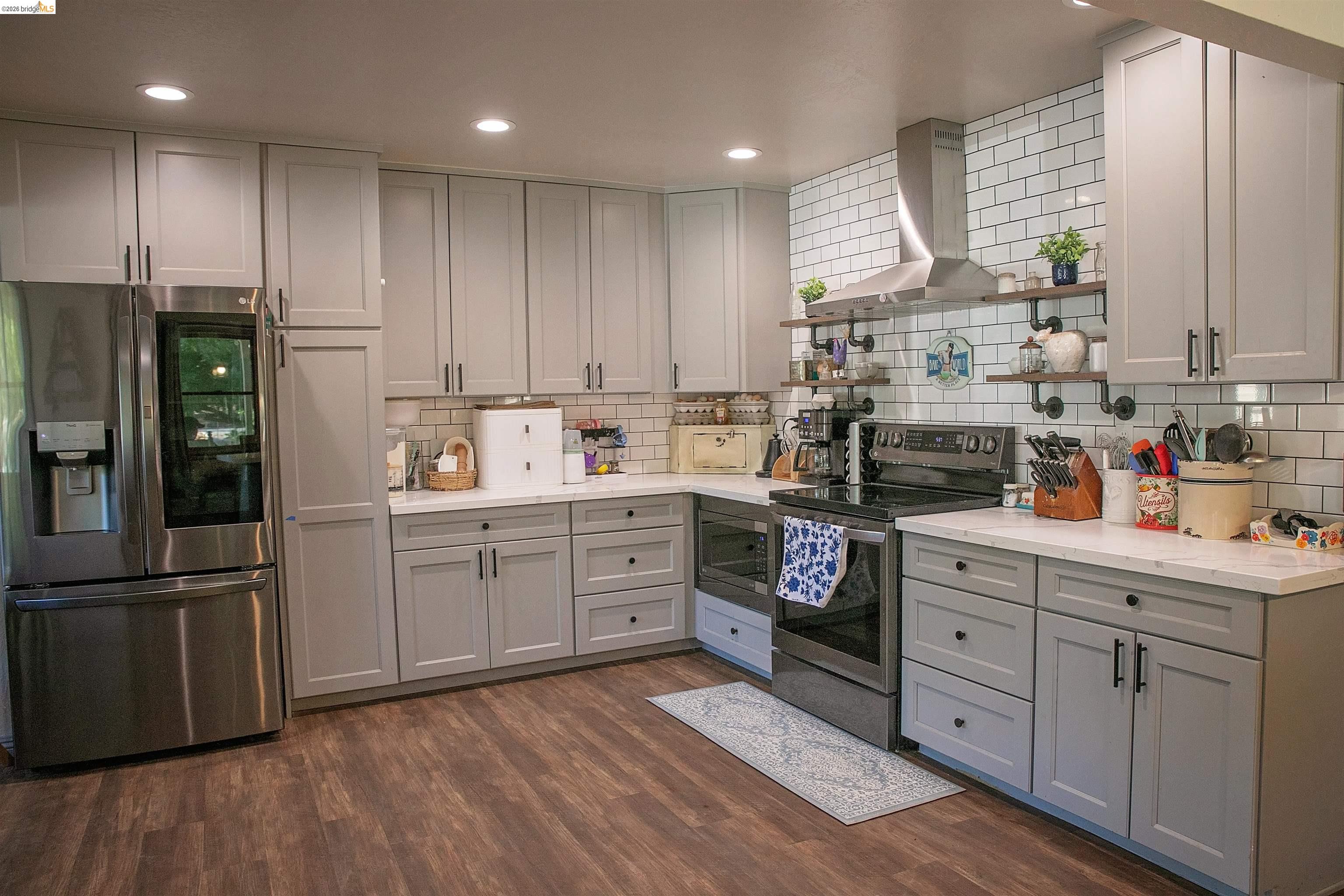 20982 Shaws Flat Road Sonora, CA 95370 - Photo 9 of 26 Contemporary kitchen featuring light gray cabinetry, stainless steel appliances, a subway tile backsplash, white countertops, and wood-finish flooring