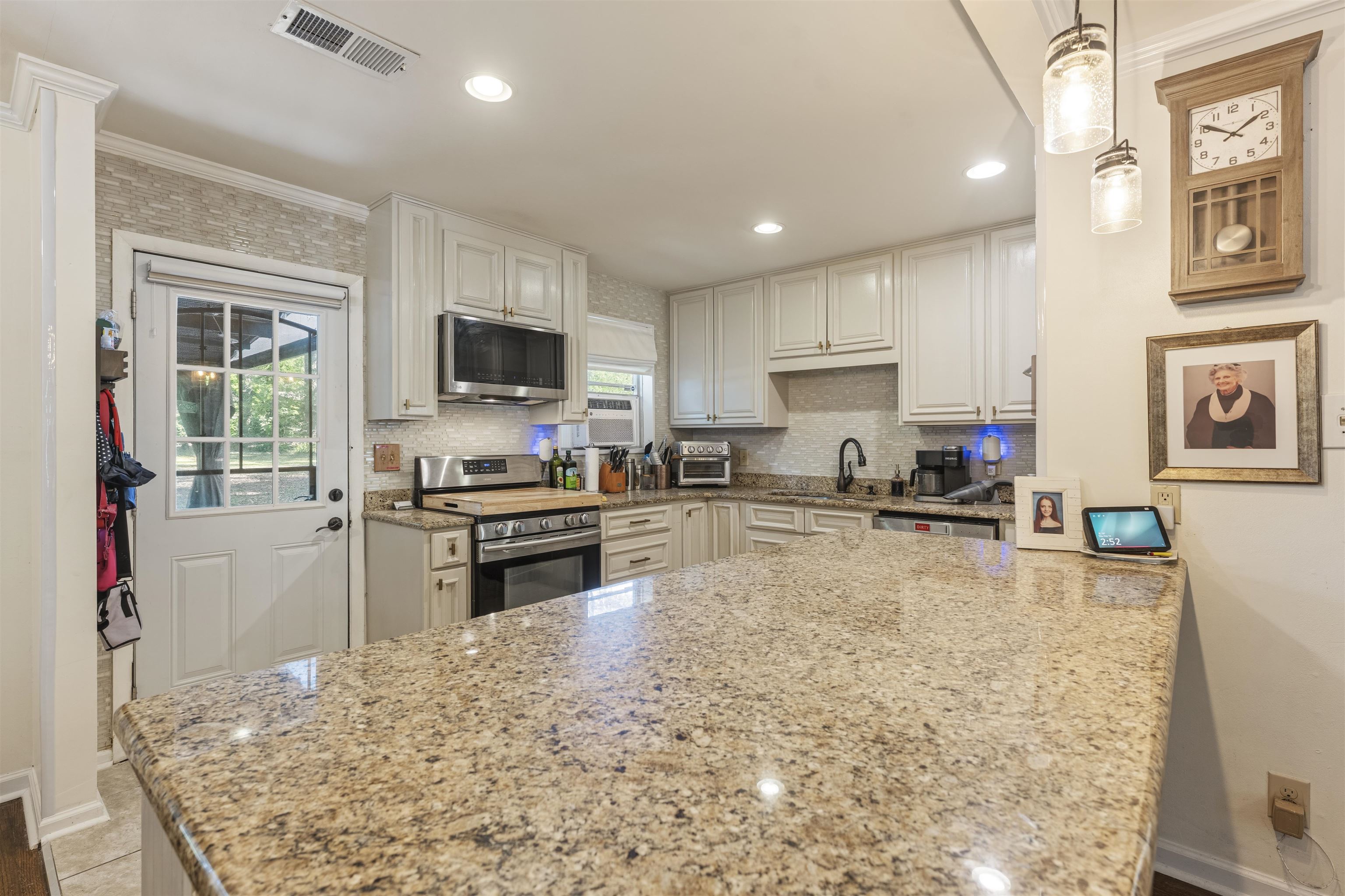 5271 Princeton Road Memphis, TN 38120 - Photo 22 of 30 Spacious kitchen featuring an expansive granite countertop, white cabinetry, stainless steel appliances, a tile backsplash, and recessed lighting