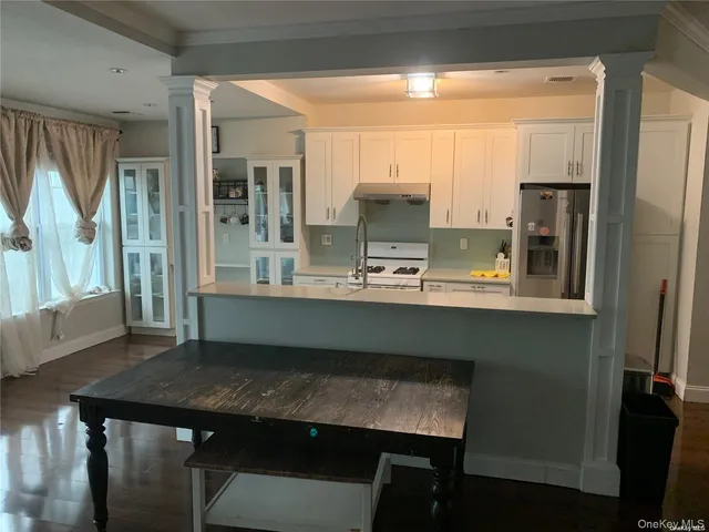 a kitchen with kitchen island a table chairs refrigerator and sink