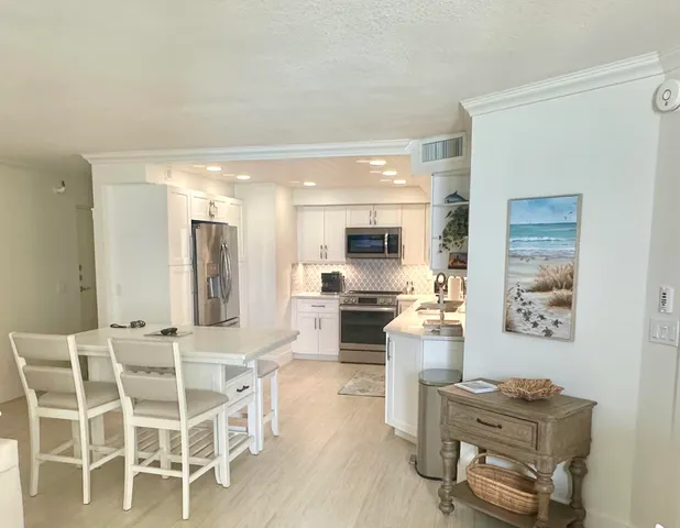 a kitchen with stainless steel appliances kitchen island granite countertop a stove and cabinets with wooden floor