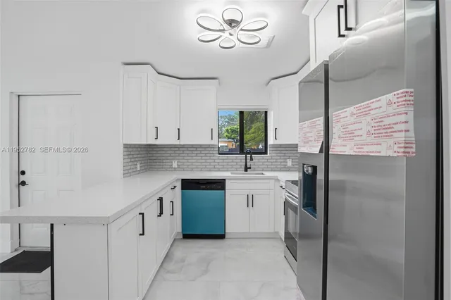 a kitchen with a sink dishwasher a stove and white cabinets