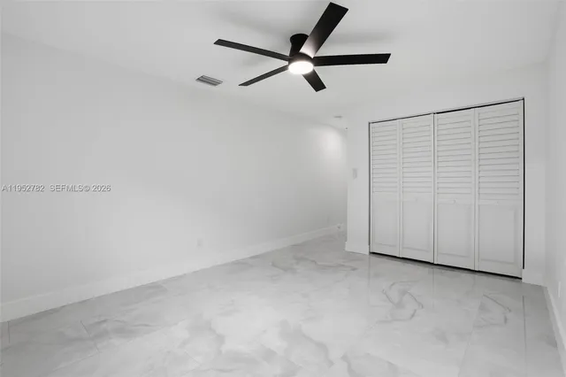 an empty room with a window and a fan