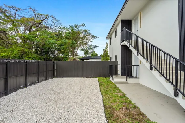 a view of backyard with wooden fence and trees