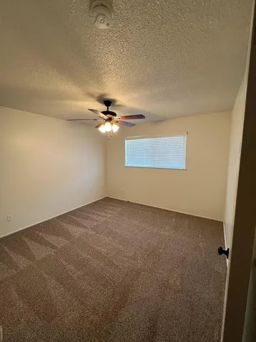 an empty room with a ceiling fan and a window