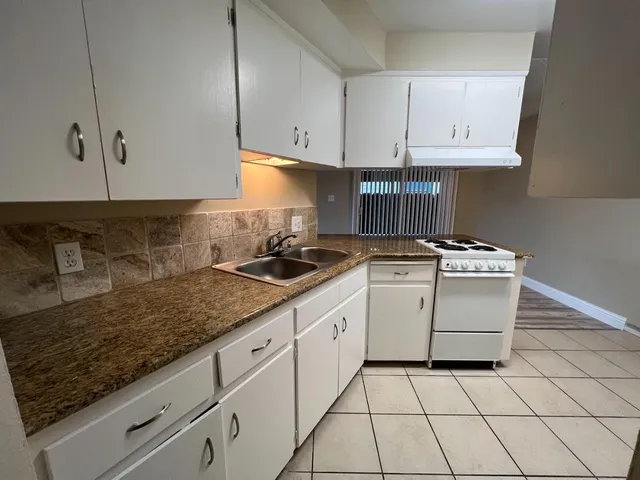 a kitchen with granite countertop white cabinets and white appliances
