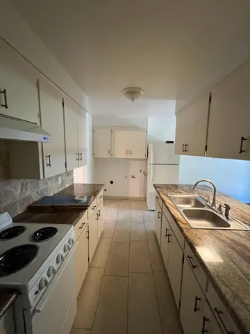 a kitchen with granite countertop a sink a stove and cabinets