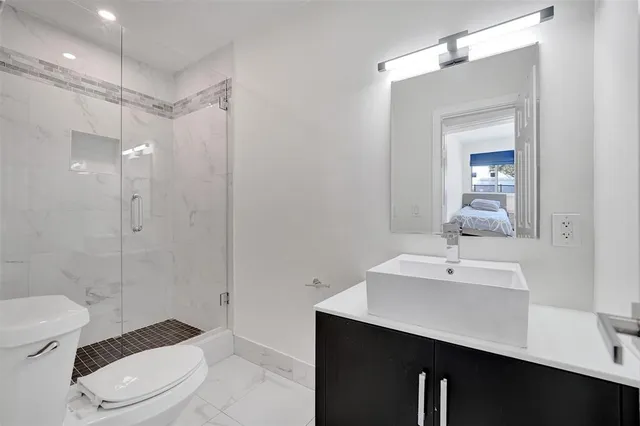 a bathroom with a sink a toilet a mirror and shower