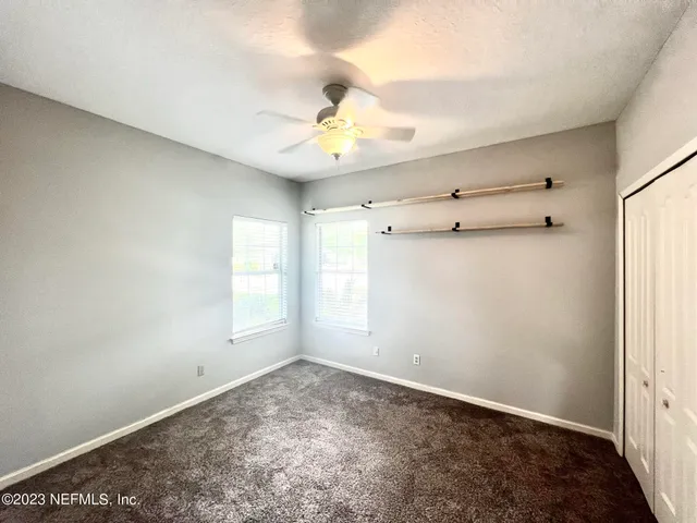 an empty room with a window and a ceiling fan