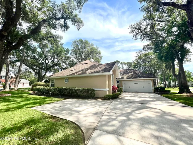 a view of a house with a yard and large tree