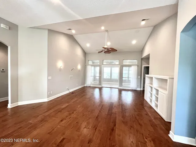 an empty room with wooden floor and windows
