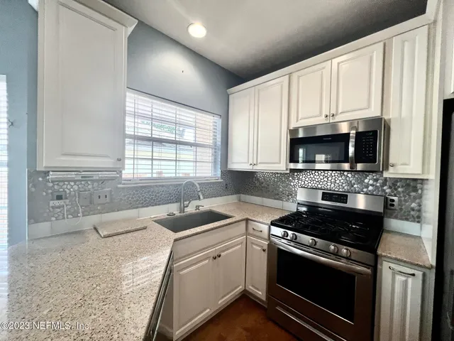 a kitchen with granite countertop a sink cabinets and stainless steel appliances