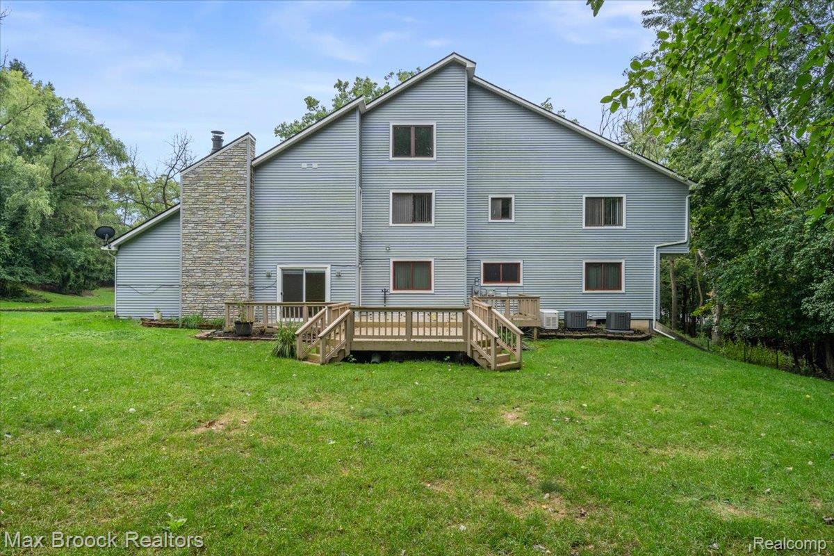 1830 Lone Pine Road Bloomfield Hills, MI 48302 - Photo 56 of 70 Multi-story exterior with siding, a prominent stone facade chimney, a wooden deck with stairs, and sliding glass doors. 2 AC Units and whole house generator.