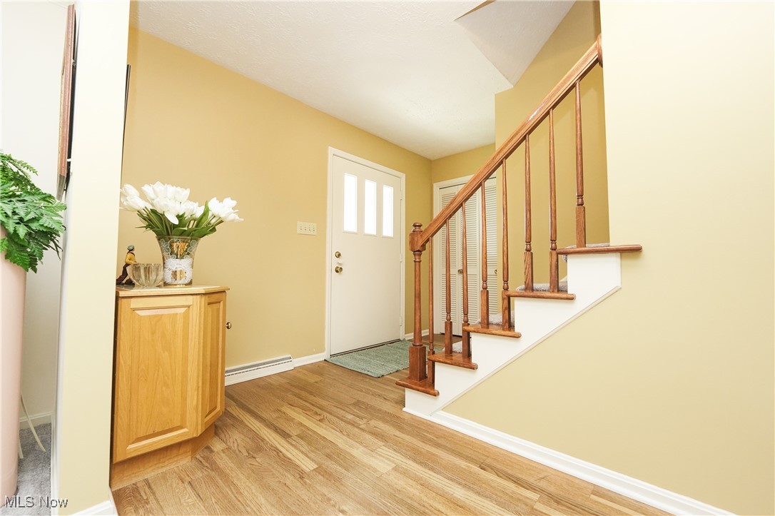 817 Rickel Circle Akron, OH 44333 - Photo 6 of 49 Entrance foyer with a baseboard heating unit, light wood-style floors, stairway, and baseboards