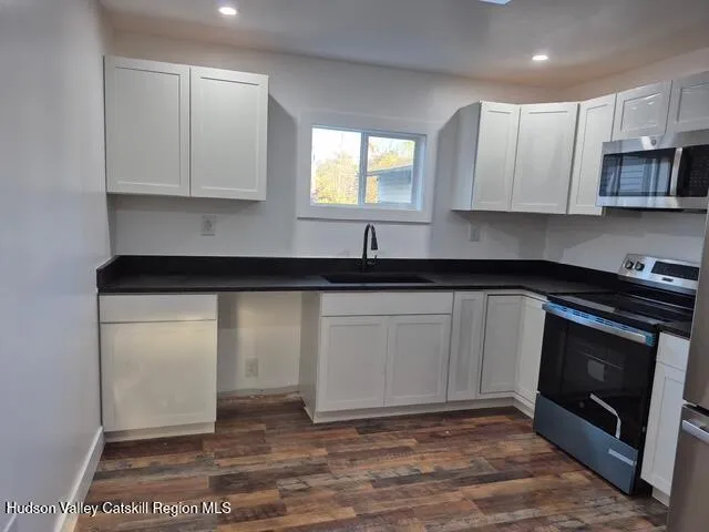 a kitchen with granite countertop white cabinets stainless steel appliances and a sink