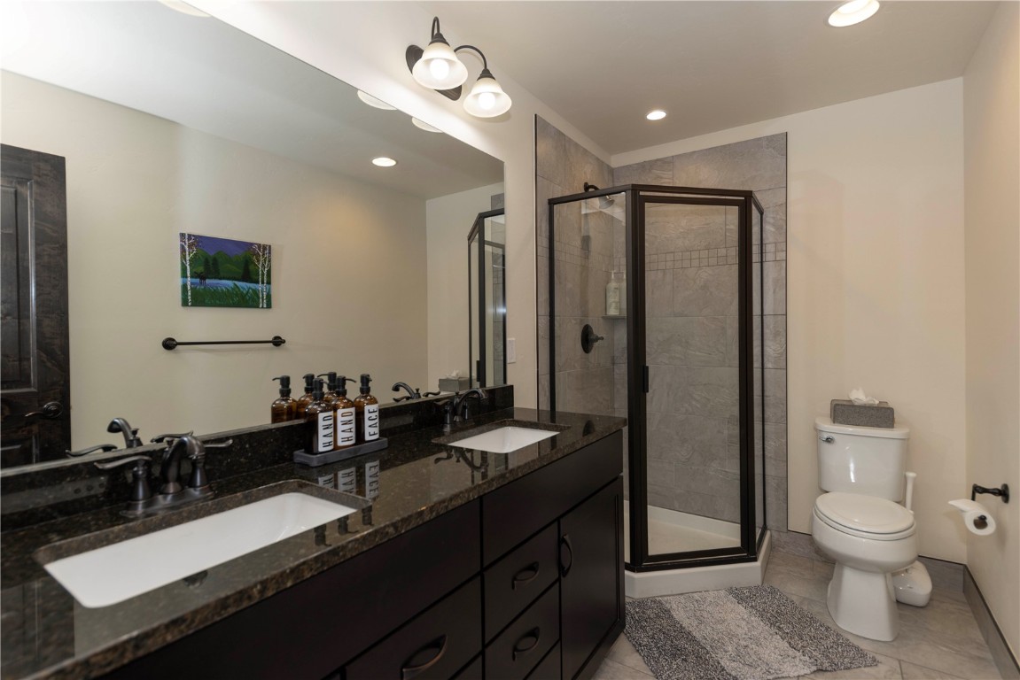 58 Erickson Loop, Unit 13A Keystone, CO 80435 - Photo 22 of 28 a bathroom with a granite countertop sink a toilet a mirror and shower