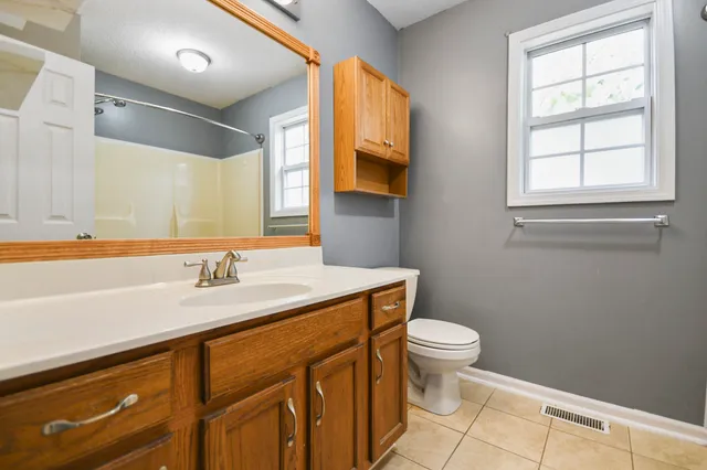 a bathroom with a granite countertop sink toilet and mirror