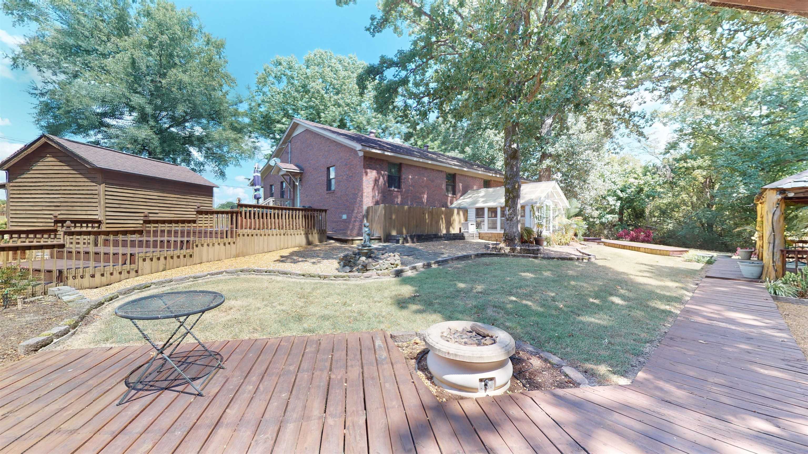 420 Joann Road Somerville, TN 38068 - Photo 28 of 40 Expansive backyard featuring a wood deck, wood-sided shed, brick exterior, and a sunroom with multiple windows
