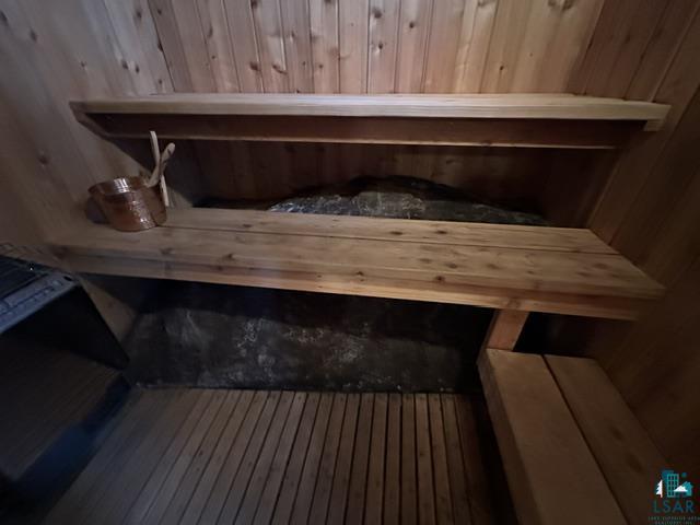 2763 Van Vac Road Ely, MN 55731 - Photo 32 of 37 Sauna room featuring multi-level wood benches, slat wood flooring, wood-paneled walls and ceiling, and a sauna heater