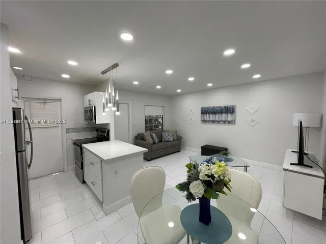 a living room with stainless steel appliances furniture a dining table and a flat screen tv