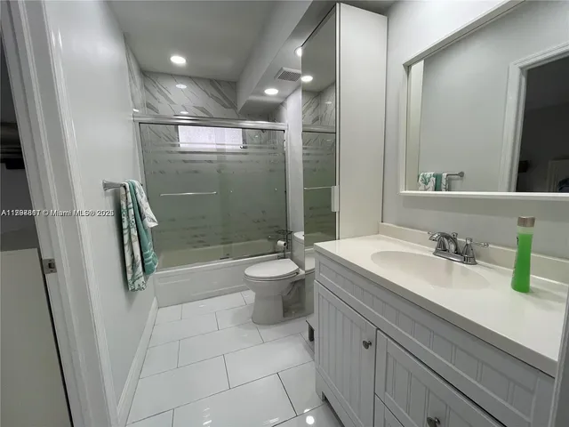 a bathroom with a granite countertop sink a toilet a mirror and shower