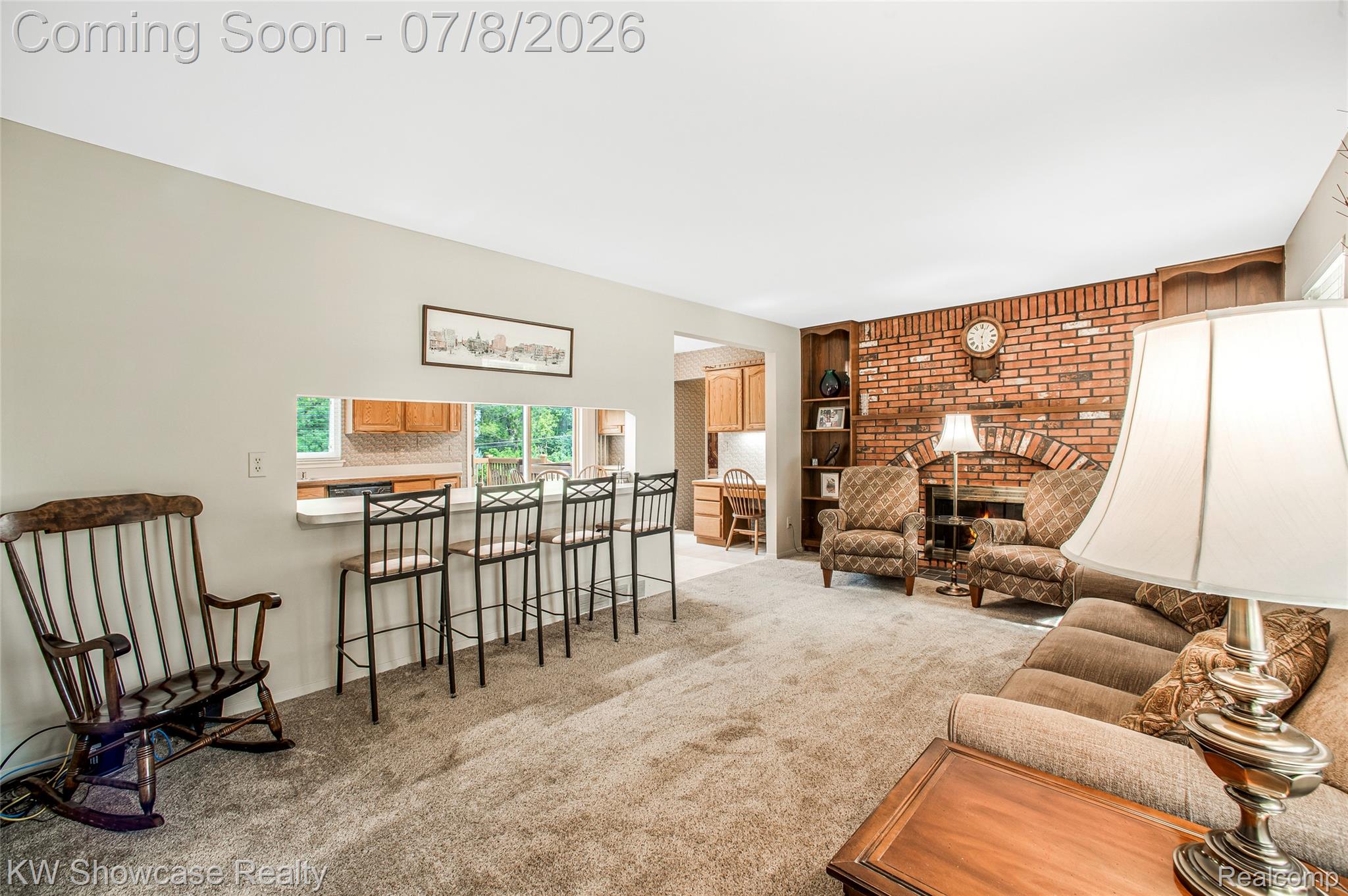 16720 Wayne Road Livonia, MI 48154 - Photo 15 of 29 Expansive living area featuring a brick fireplace with an arched opening, built-in shelving, a pass-through window to the kitchen, and light-toned carpeting