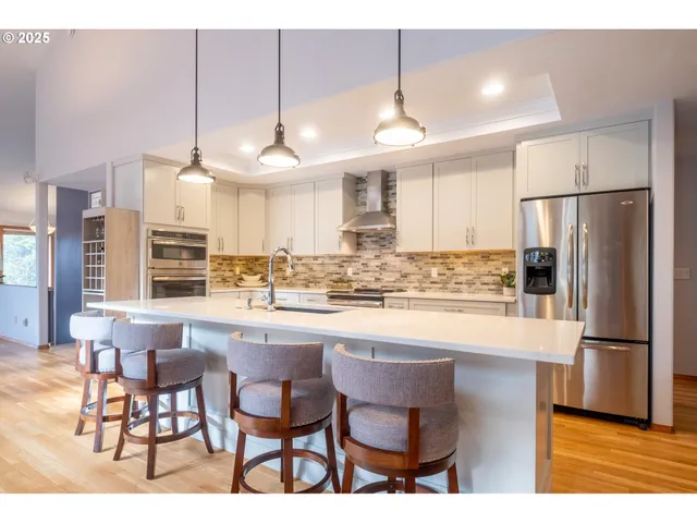 a kitchen with stainless steel appliances a dining table chairs refrigerator and sink