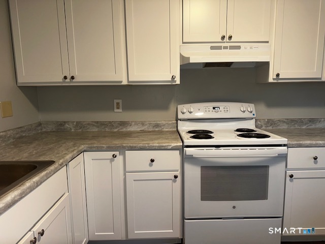 7 Padanaram Road, Unit J232 Danbury, CT 06811 - Photo 3 of 26 a kitchen with granite countertop white cabinets and white appliances