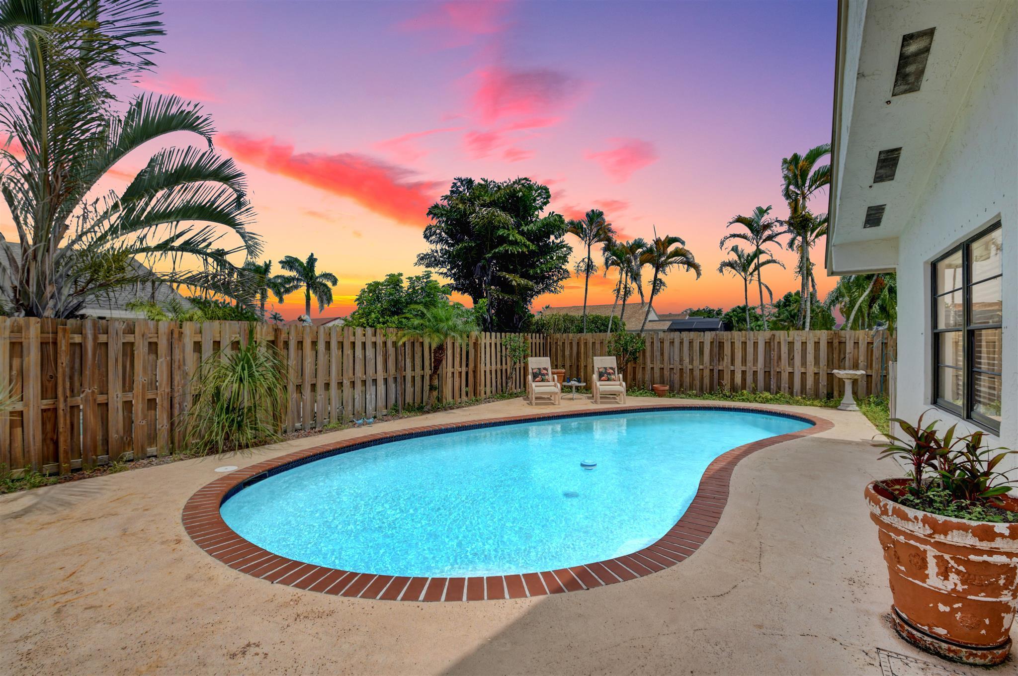 21080 Windemere Lane Boca Raton, FL 33428 - Photo 44 of 97 a view of a swimming pool with a lounge chair and palm trees