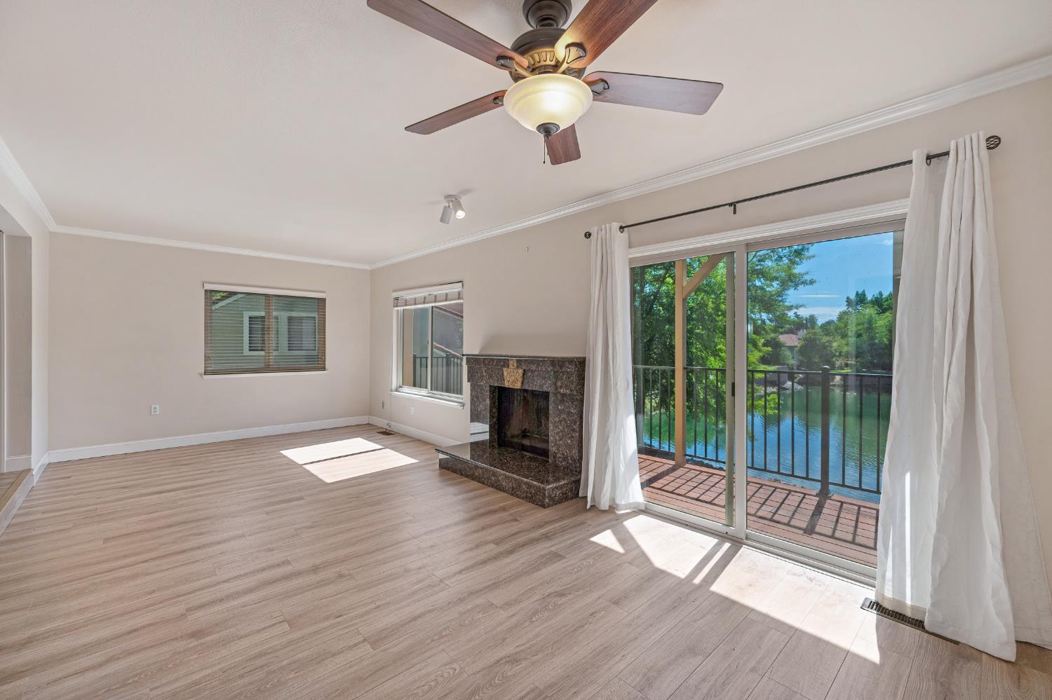 6986 Carreta Lane Rancho Murieta, CA 95683 - Photo 11 of 47 a view of an empty room with wooden floor fireplace and a window