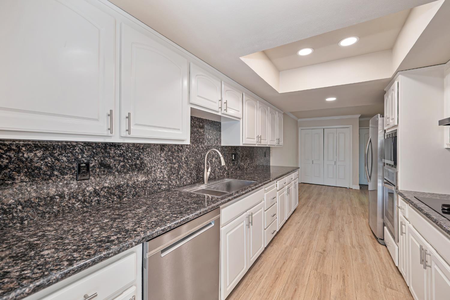 6986 Carreta Lane Rancho Murieta, CA 95683 - Photo 13 of 47 a kitchen with granite countertop a sink a counter space stainless steel appliances and cabinets